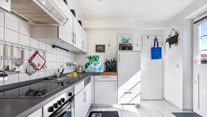 Eine moderne Küche mit weißen Schränken, einer schwarzen Arbeitsplatte und einem schwarzen Teppich mit dem Aufdruck 'Kitchen'.