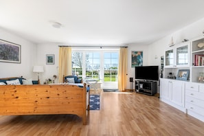 Une pièce spacieuse avec un lit en bois, une télévision, un bureau et une vue dégagée grâce à de grandes fenêtres.