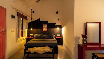 A bedroom with a bed, bedside tables, a mirror, a ceiling fan, and a window.