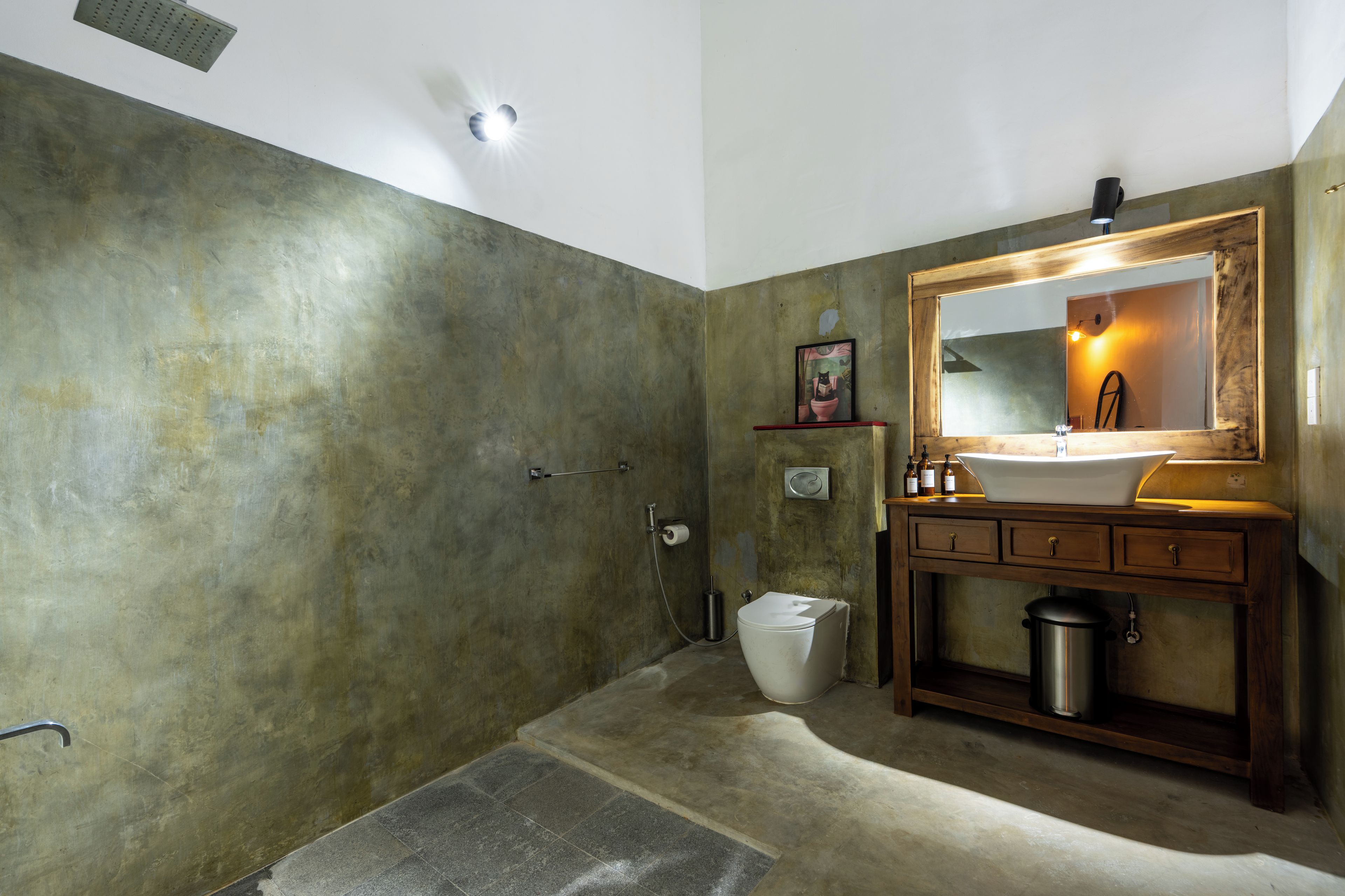 Een badkamer met douche, toilet, wastafel en een spiegel met een lijst.