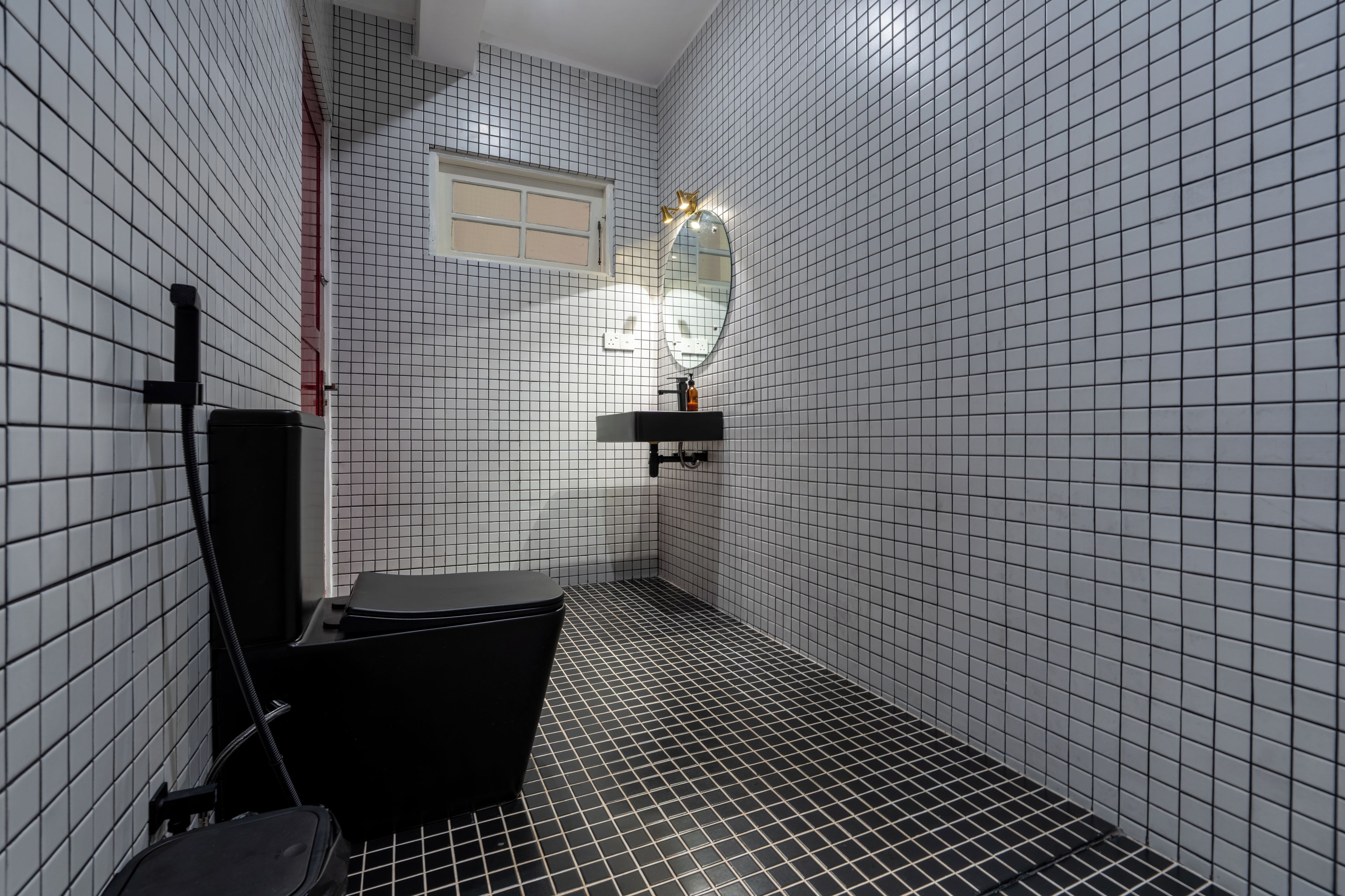 Une salle de bain avec des toilettes noires, un miroir et un lavabo équipé d’un distributeur de savon.