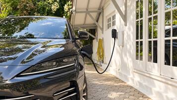 A black car parked in a driveway with a charging station.