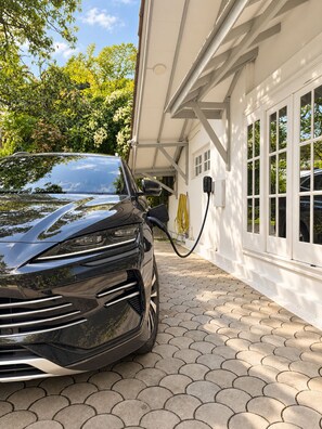 A black car parked in a driveway with a charging station. - Hebron Gardens House  (Kandy)