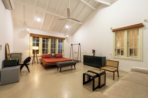 A spacious room with a bed, a desk, a chair, a sofa, and a window with a view. - Hebron Gardens House  (Kandy)