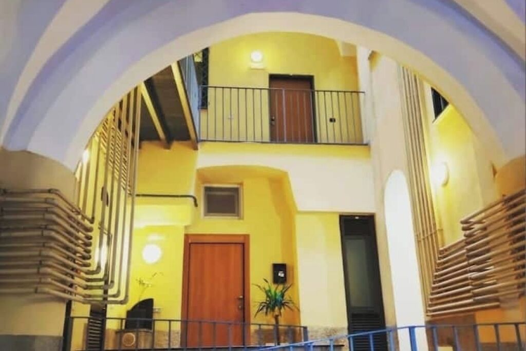 Ein mehrgeschossiges Interieur mit gelber Wand, Holztür und einer Treppe.