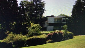 A modern two-story house surrounded by lush greenery and trees. - Spacious, bright apartment near Paris (Louveciennes)