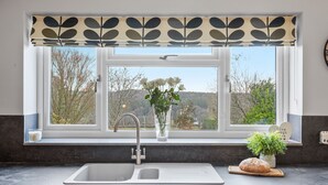 A kitchen with a window, sink, and a decorative plant. - Newlands (Yelverton)