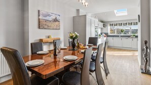 A modern dining area with a wooden table, black chairs, and a painting on the wall. - Newlands (Yelverton)