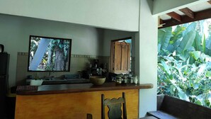 Una cocina con mostrador de madera, un lavamanos y un ventanal con vistas a vegetación.