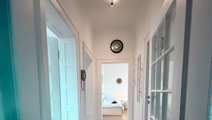 A hallway with wooden flooring, white walls, and doors leading to a bedroom. - sleepWELL-Nordhorn - Large & modern central location (Nordhorn)