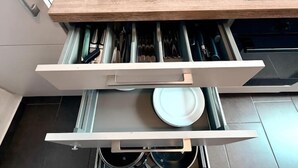 A kitchen with a microwave, a stove, and a drawer with utensils. - sleepWELL-Nordhorn - Large & modern central location (Nordhorn)