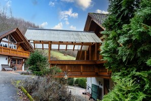 Un chalet in legno con un balcone, un portico coperto e vista su un paesaggio collinare.
