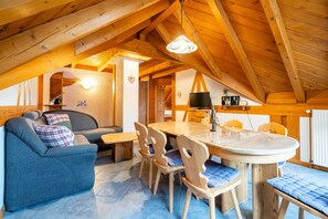 Un'accogliente stanza con arredamento in legno, dotata di divano, tavolo da pranzo, sedie e televisione.