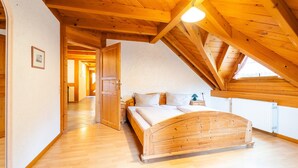 Un dormitorio con techo de madera, una cama y una ventana.
