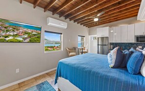 Un dormitorio con cama, vistas al mar, comedor y cocina.