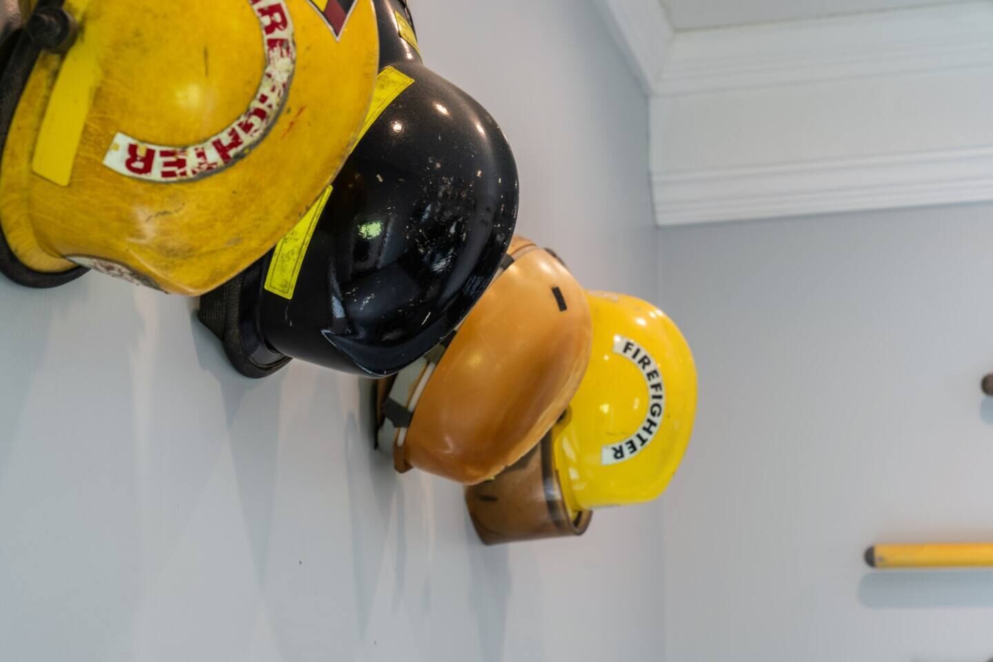 A wall-mounted fire extinguisher with a yellow label and a black helmet.