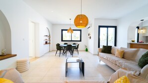 A modern living room with a sofa, a coffee table, and a dining area with chairs and a table. - Residence Jannet 1 Luxury Seaside 3 Bedrooms (Hammamet)