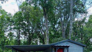Un petit bâtiment d’un seul étage, avec une porte rouge et une véranda couverte.