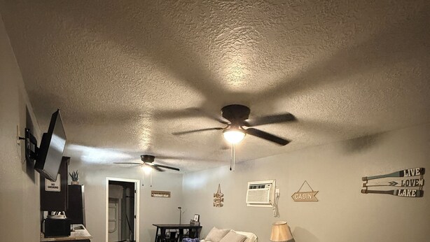 Une chambre d’hôtel avec deux lits, un ventilateur de plafond, un téléviseur fixé au mur et un panneau indiquant un espace réservé aux fumeurs.