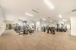 A spacious gym with various exercise machines, a clear path for walking, and a bright, well-lit environment. - Chic Urban Condo in Heart of Burnaby (Burnaby)