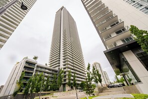 Moderni, korkea kerrostalo, jonka ainutlaatuinen kulmikas muotoilu erottuu, ja jonka ympärillä on muita nykyaikaisia rakennuksia ja viheralueita.