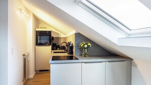 Een moderne keuken met dakraam, witte kasten en een vaas met bloemen.