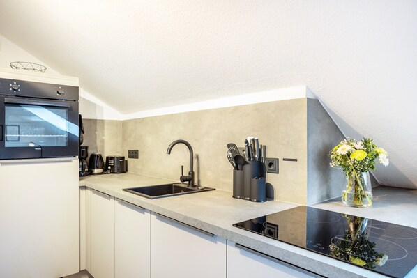 A modern kitchen with a built-in oven, a sink, and a countertop with a vase of flowers.