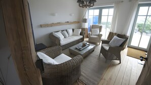 A living room with a sofa, armchairs, a coffee table, and a chandelier. - Port on the Fehmarnsund – Sea View and Beach at Your Doorstep (Fehmarn)