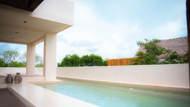 Un área de piscina moderna al aire libre con una vista despejada del cielo y vegetación circundante.