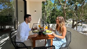 Un balcón con una mesa dispuesta para dos personas, mostrando una comida y bebidas.
