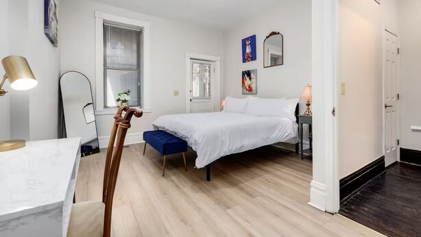 Une chambre à coucher avec un lit, une table de chevet, une lampe et une fenêtre avec des stores.