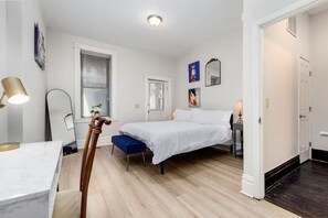 Un dormitorio con cama, mesita de noche, lámpara y ventana con persianas.