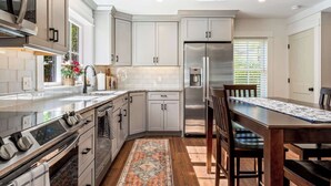 Una cocina moderna con armarios blancos, electrodomésticos de acero inoxidable y una mesa de comedor de madera.