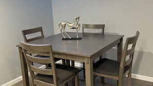 A dining table with four chairs, a decorative horse sculpture, and a blue LED light strip along the ceiling.