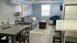 A compact living space with a dining area, sofa, and a small kitchen.