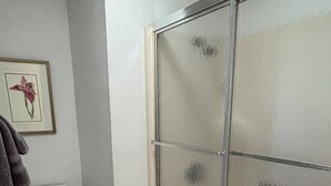 Une salle de bain comprenant des toilettes, un espace douche et un tableau encadré au mur.