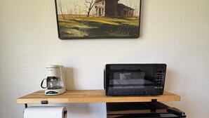 Une petite cuisine équipée d’un four à micro-ondes, d’une machine à café et d’un distributeur d’essuie-tout.