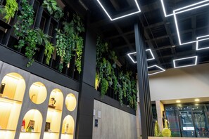 Ein modernes Interieur mit vertikalen Gärten, beleuchteten geometrischen Deckenstrukturen und runden Leuchten.