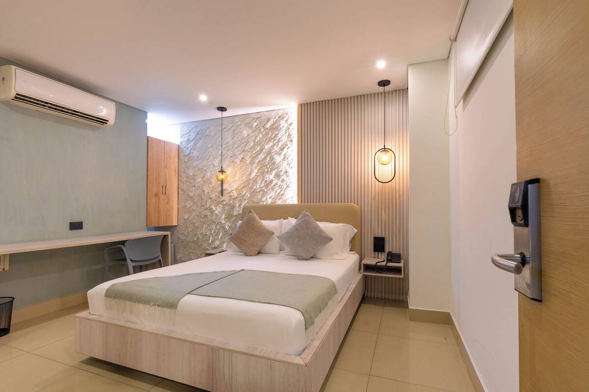 A modern bedroom with a bed, desk, and seating area.