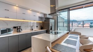 A modern kitchen with a central island, built-in appliances, and a large window offering a city view. - Hotel Time Oclock (Medellín)