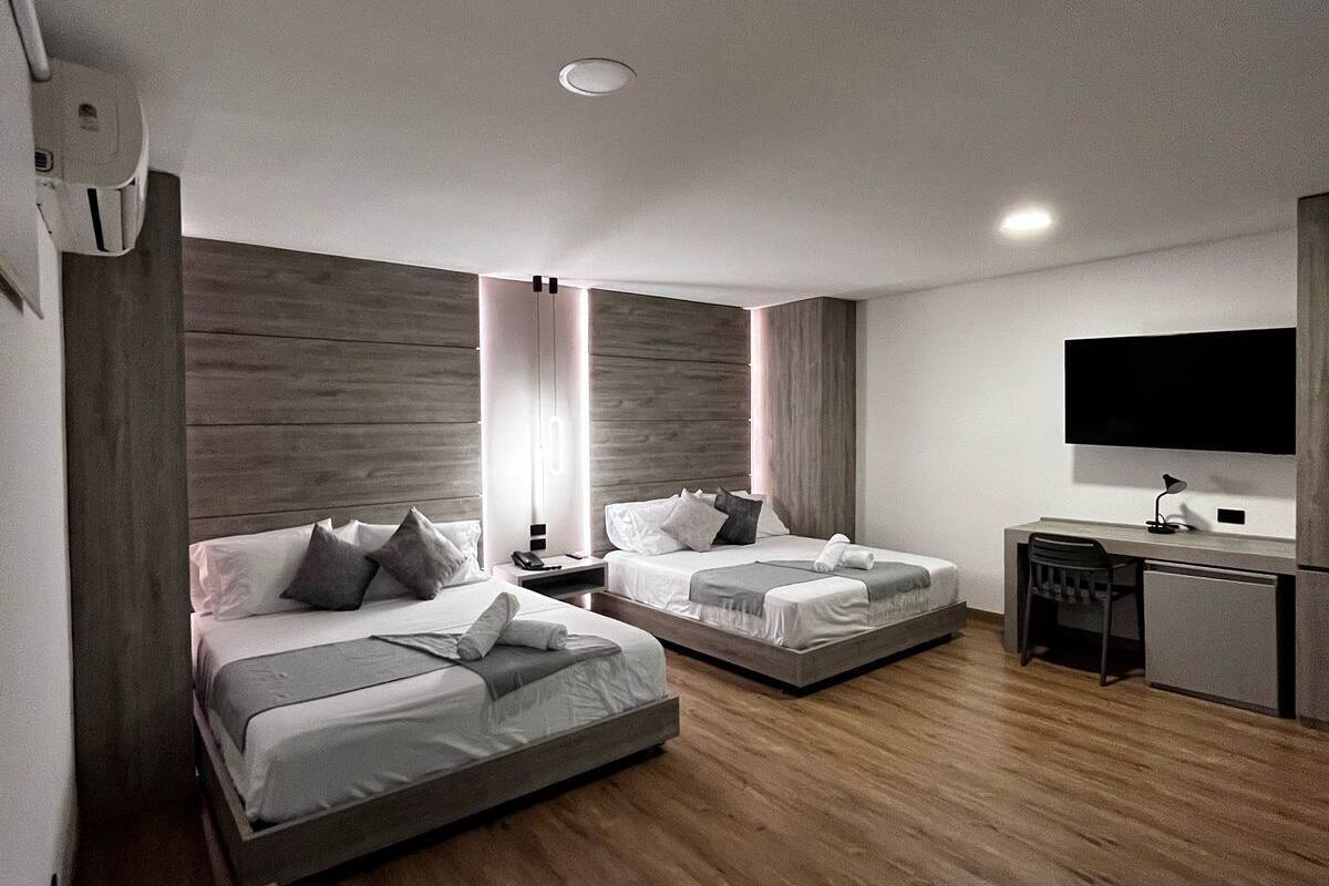A modern hotel room with two beds, a desk, a chair, and a TV.