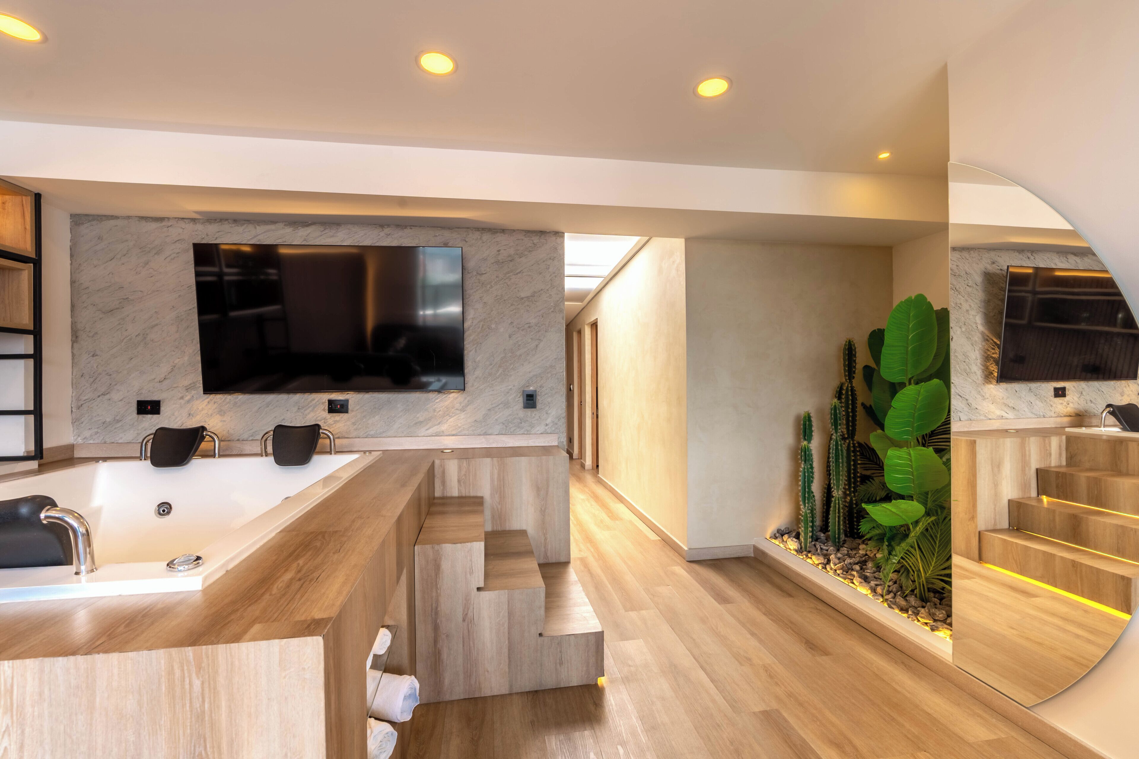 A modern bathroom with a large mirror, a bathtub, and a wooden vanity.