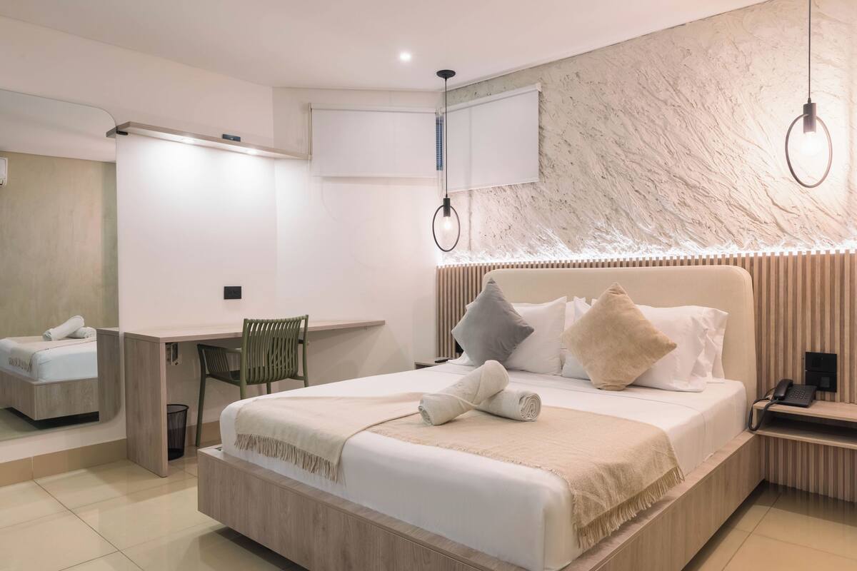 A modern hotel room with a large bed, a desk, and a chair.