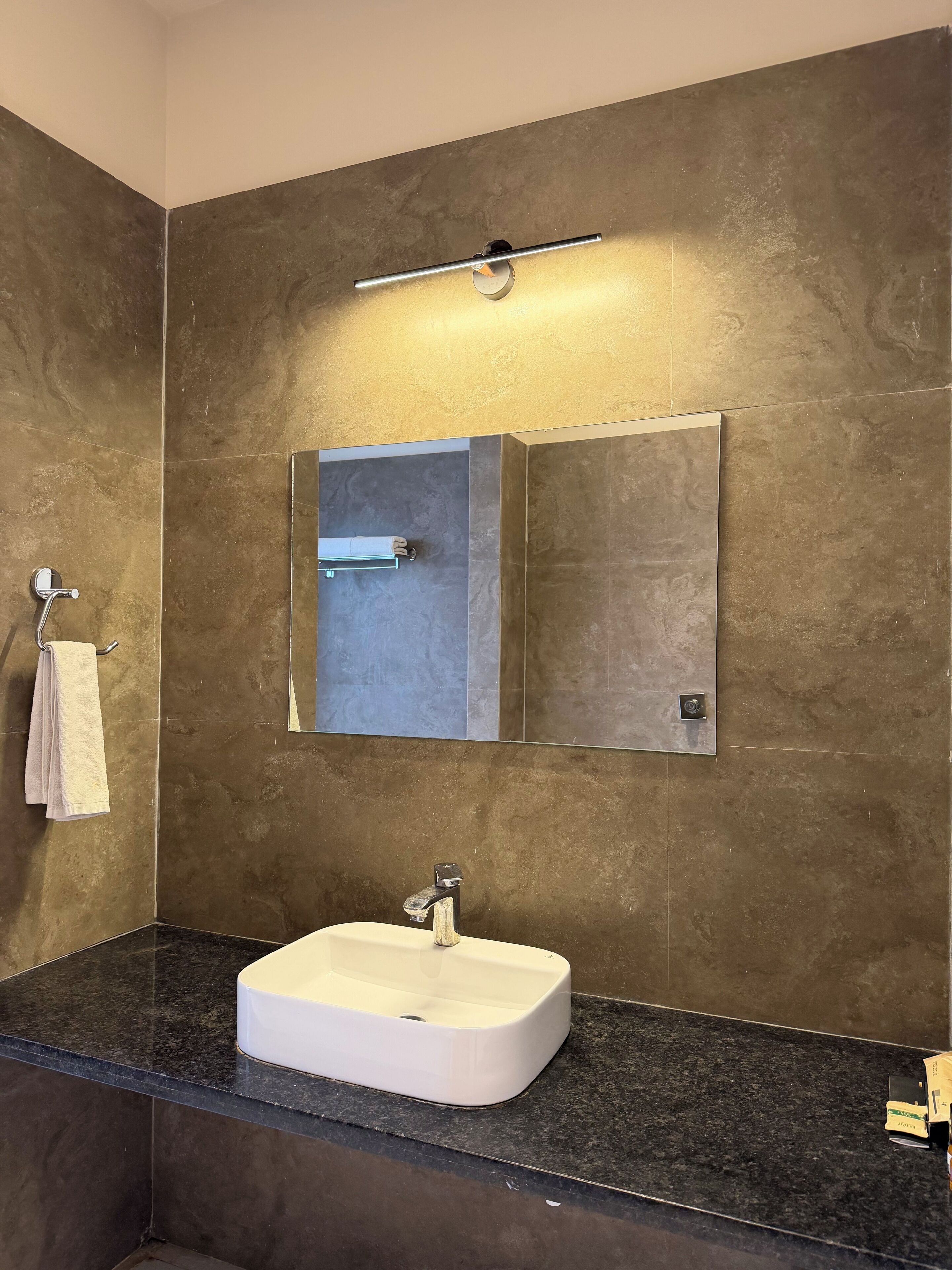 Een moderne badkamer met een witte wastafel, een handdoekhouder en een spiegel.