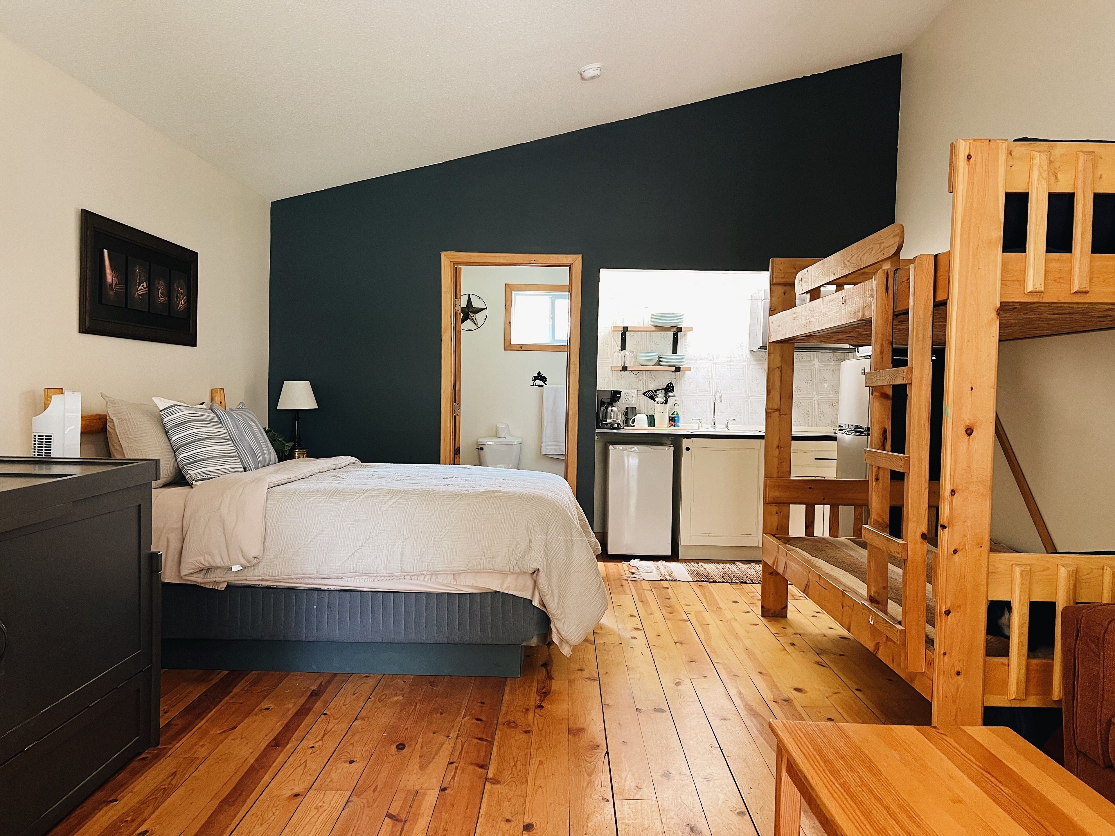 A bedroom with a bed, bedside table, and a wooden bunk bed.
