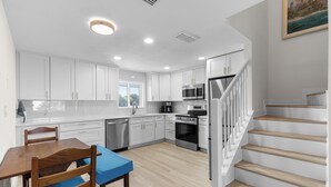 Una cocina moderna con armarios blancos, electrodomésticos de acero inoxidable y una mesa de comedor de madera.