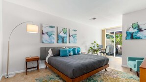 Un dormitorio moderno con una cama grande, una lámpara de pie y arte abstracto en la pared.
