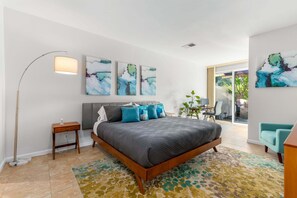 Un dormitorio moderno con una cama grande, una lámpara de pie y arte abstracto en la pared.