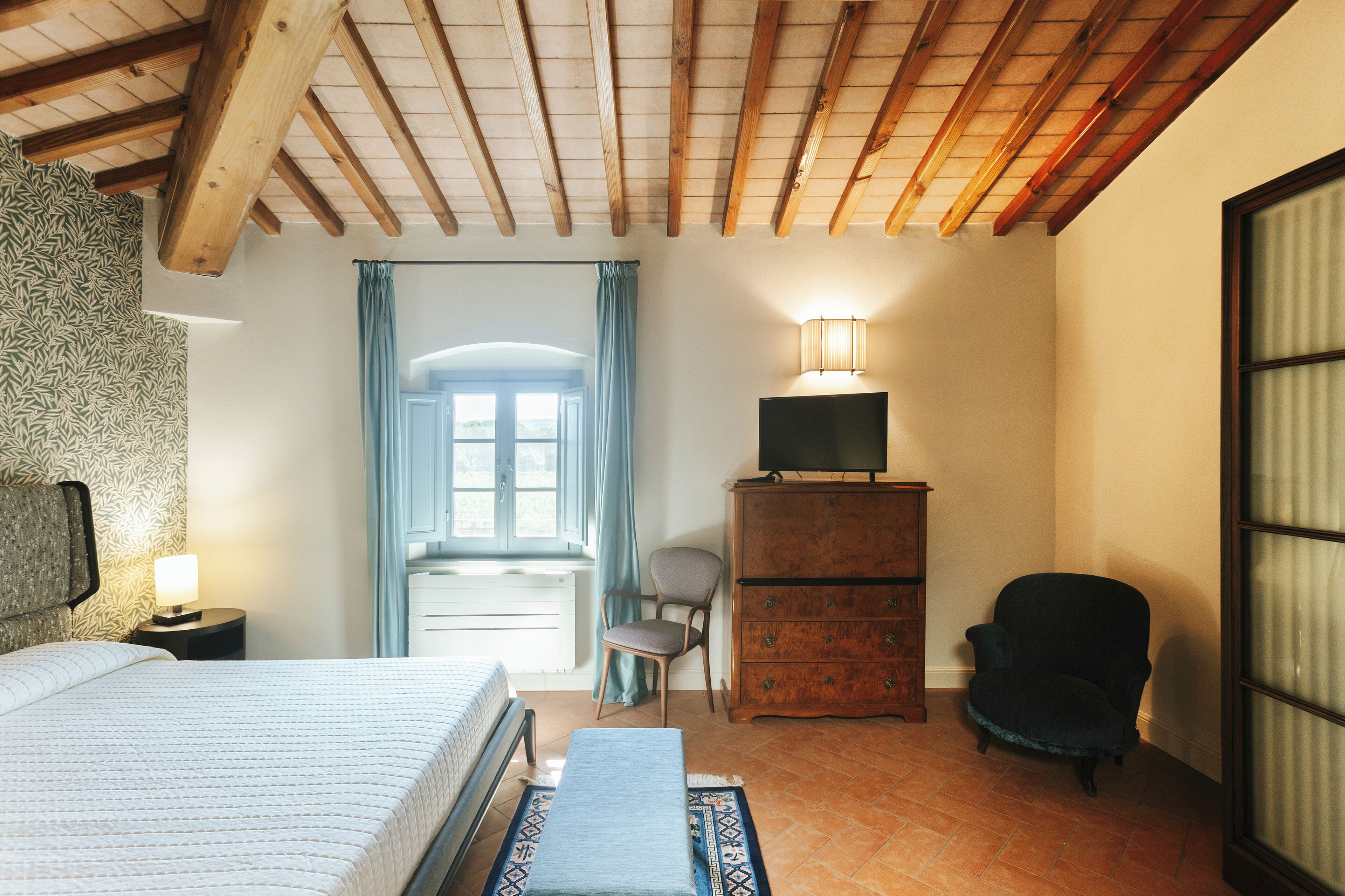A bedroom with a bed, a dresser, a chair, a desk, and a window with curtains.