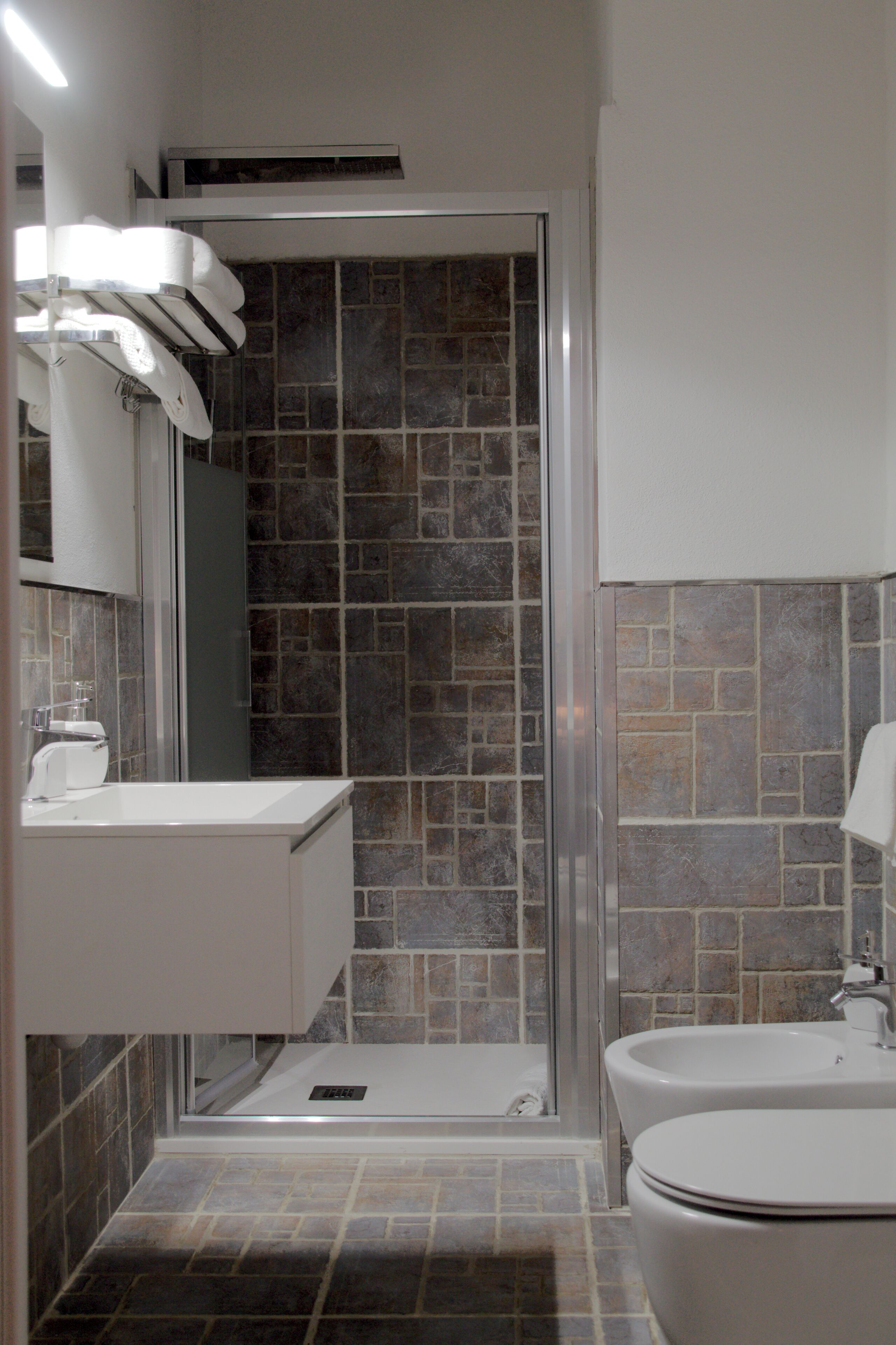 A modern bathroom with a shower, a sink, and a toilet.